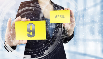 April 9th. Day 9 of month, Calendar date. Business woman hand hold yellow sheet with calendar date...
