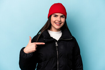 Young caucasian woman isolated on blue background person pointing by hand to a shirt copy space, proud and confident