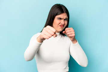 Young caucasian woman isolated on blue background showing fist to camera, aggressive facial...