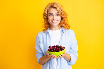 Charming woman with cherry plate isolated on yellow. © Olena