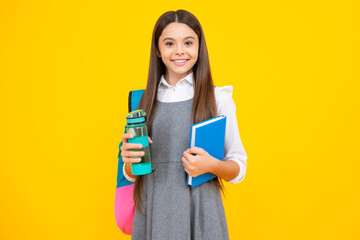 Teenager school girl with backpack holding water bottle isolated on yellow background.