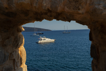 View of yachts in Bodrum Marina, Aegean Sea, Turkey through loopholes of walls of Bodrum Castle or...