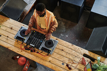 Above view of young African American male musician creating new music at lesire while touching...