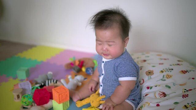 asian baby sneezing while playing with toys