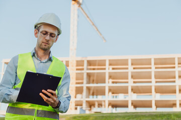 Engineer builder in white hat with folder at construction site