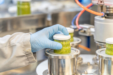 Pesto sauce Industrial process. High quality sauce production. Factory worker working on vacuum...