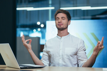 Fototapeta premium Business man working in a modern office, meditating and practicing yoga at the table, relaxing and calming relieves stress