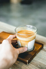 hand picking up the cup of dirty coffee. Special menu.