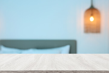 Wooden table and blurred bedroom background, bright morning light. Product display or mock up