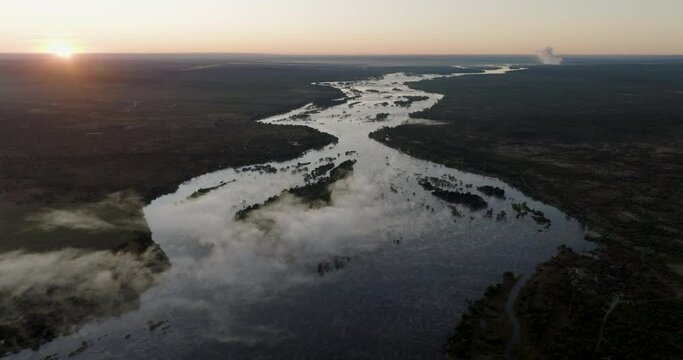 High aerial sunrise fly over view of the mist on the mighty Zambezi River flowing down to the Victoria Falls, Unesco world heritage site