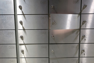 Deposit boxes (safe cells) with numbers and keys in keyholes in a bank, one cell is opened, closeup - 510669137
