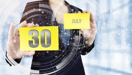July 30th. Day 30 of month, Calendar date. Business woman hand hold yellow sheet with calendar date on blurred office background. Summer month, day of the year concept.