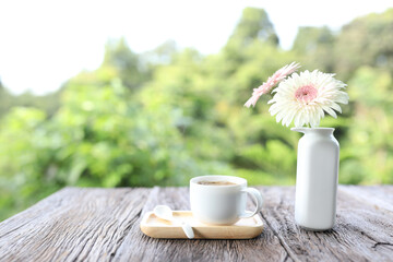 White cup and white gerbera flower on wooden table
