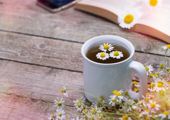 Obraz na płótnie Canvas A cup of chamomile tea on the reading table
