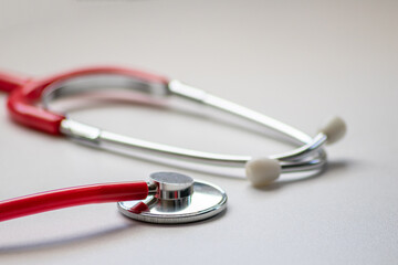 Red stethoscope in doctors office for professional cardio checkup and healthy heartbeat pulse check by cardiologist in clinical treatment room on white desk as medical equipment to measure body params