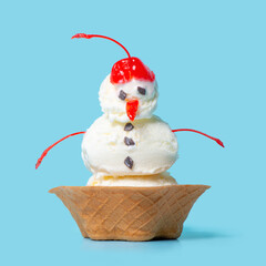 summer funny creative concept of scoops with snowman ice cream in waffle cup isolated on blue...