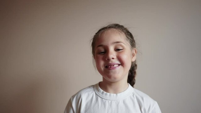 little girl smiling holding a glass of water. the child looks close-up into the video camera. happy family childhood dream concept. portrait girl daughter lifestyle smiling funny indoors