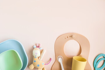 Baby accessories and tableware for food on beige background. First feeding for kids concept. Flat...