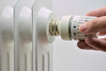 Mano regulando un termostato de un radiador - obrazy, fototapety, plakaty