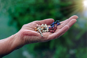 close-up of older womans hand holding a rosary