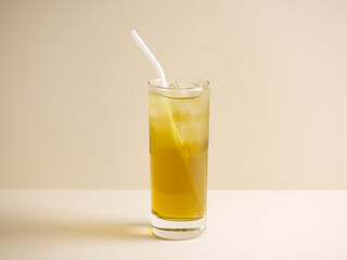 A glass of Watercress Honey Lemon Drink with straw isolated on grey background side view