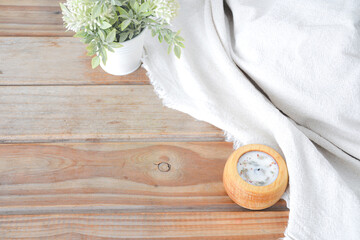 Linen fabrics with flowers and candle on wooden background
