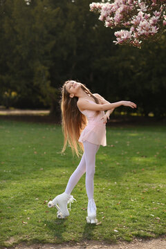 Beautiful girl with long hair in the park. Girl on roller skates. The girl smiles. Quad rollers.
