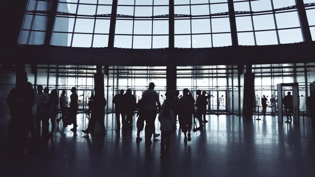 Silhouettes of unknown people in the hall and glass doors of a modern building