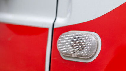 Automotive light bulb. Turn signal on the side of the car. A white turn signal on a red crossover,...