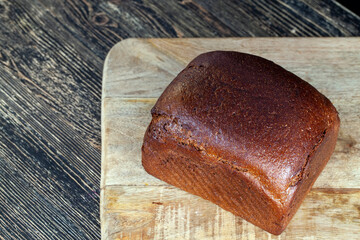 a square rye loaf of bread on a cutting board