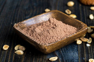 cocoa powder and a wooden bowl and roasted peanuts on the table