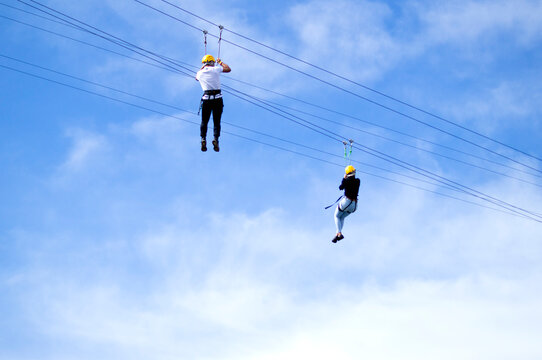 Couple Practicing Zipline Under Blue Sky With Clouds