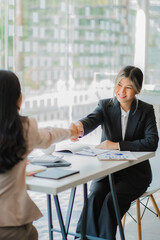 Young Asian businesswoman and interviewer shaking hands in modern office Business meeting, greetings, agreements, ideas after negotiating with her partner. Teamwork and Success Concept