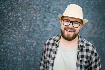 Handsome guy tourist looking happy wearing straw hat for travelling, standing against concrete wall background with copy space