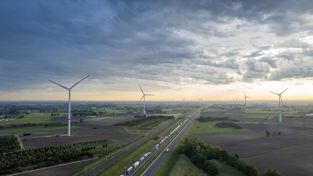 Panoramic aerial drone view of wind farm or wind park, with high wind turbines for generation electricity with the motorway with few cars and railroad next to it, near the exit of Brecht in Belgium