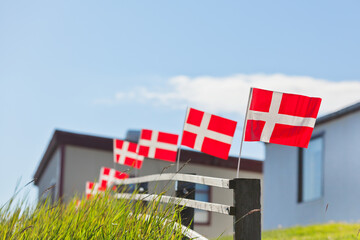 Danish flags in a row on a wooden fence in a village