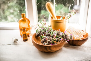 Honey plant Wild basil , Clinopodium vulgare or Satureja vulgaris next to honeycomb honey on a wooden plate near the window