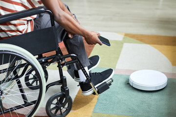 Close up man with disability using robot vacuum cleaner and smart home technology, copy space