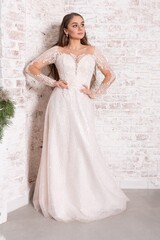 Bride in a white dress against a brick wall.