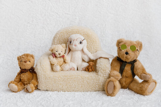 Shoot set up with sofa, teddy bears and bunny on white background. Photo zone for a photo session of newborns. Setup ready for newborn photo shoot and baby photography.