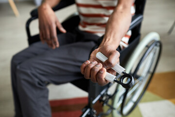 Plakat Closeup of man in wheelchair exercising hand and arm muscles by using hand expander