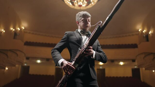 talented bassoonist with bassoon on scene of old opera house or music hall, portrait of musician