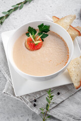 Fish cream soup with seafood in a white bowl decorated with crackers with red caviar, top view
