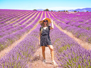 Close up of a young girl in a floral dress with a hat on her head between lavender in southern Provence Valensole France
