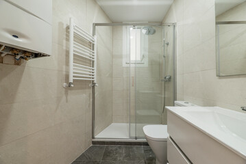 Fototapeta na wymiar Newly renovated toilet with glass partition with sliding doors, white towel rail, polished marble walls and gray floors