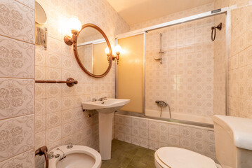 Vintage bathroom with kitsch tiles, cream-colored toilets and aluminum screen