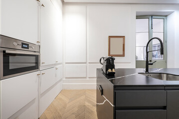 Island of a kitchen with modern decoration and furniture with black marble countertop and white wooden furniture