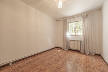 Empty living room with sintasol floors similar to parquet, window with bars and curtains with aluminum radiator