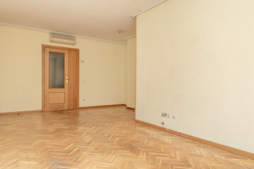 Empty living room with oak parquet flooring with matching wooden doors, air conditioner and plaster molding ceilings