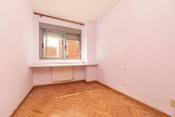 Empty room with oak parquet floor, sliding aluminum window, wall to wall study table and underfloor radiator